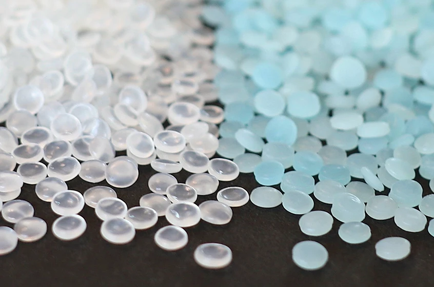 Close-up of translucent and light blue plastic LLDPE pellets, used as a raw materials in the manufacturing process of film, heavy duty film, and other plastic applications.
