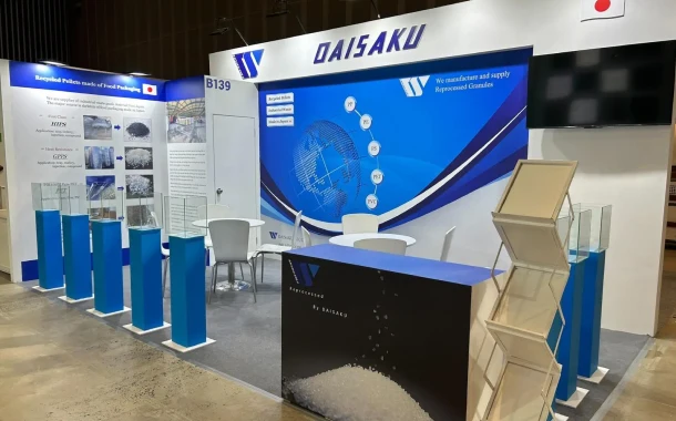 A well-designed exhibition booth for DAISAKU CO., LTD., displaying information about premium reprocessed granules and recycled materials, with product samples in glass cases and branding prominently featured.