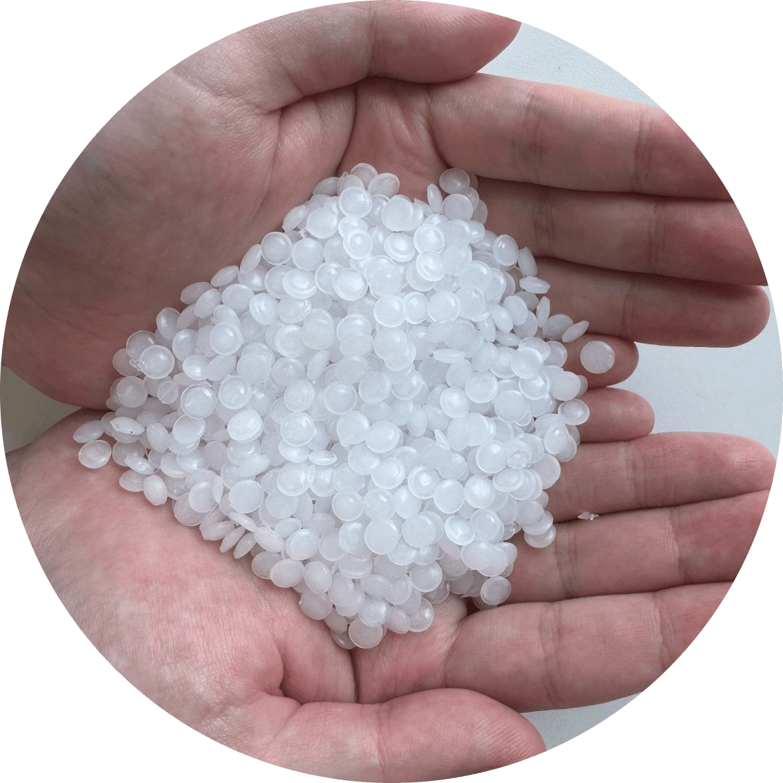 A hand holing clear plastic pellets, used as raw materials in plastic manufacturing.